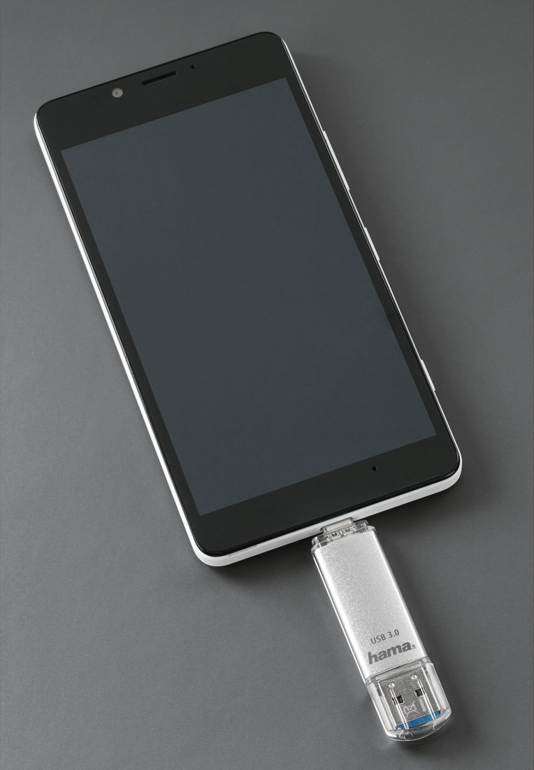 Un smartphone connecté à une clé USB, les deux sur une surface grise.