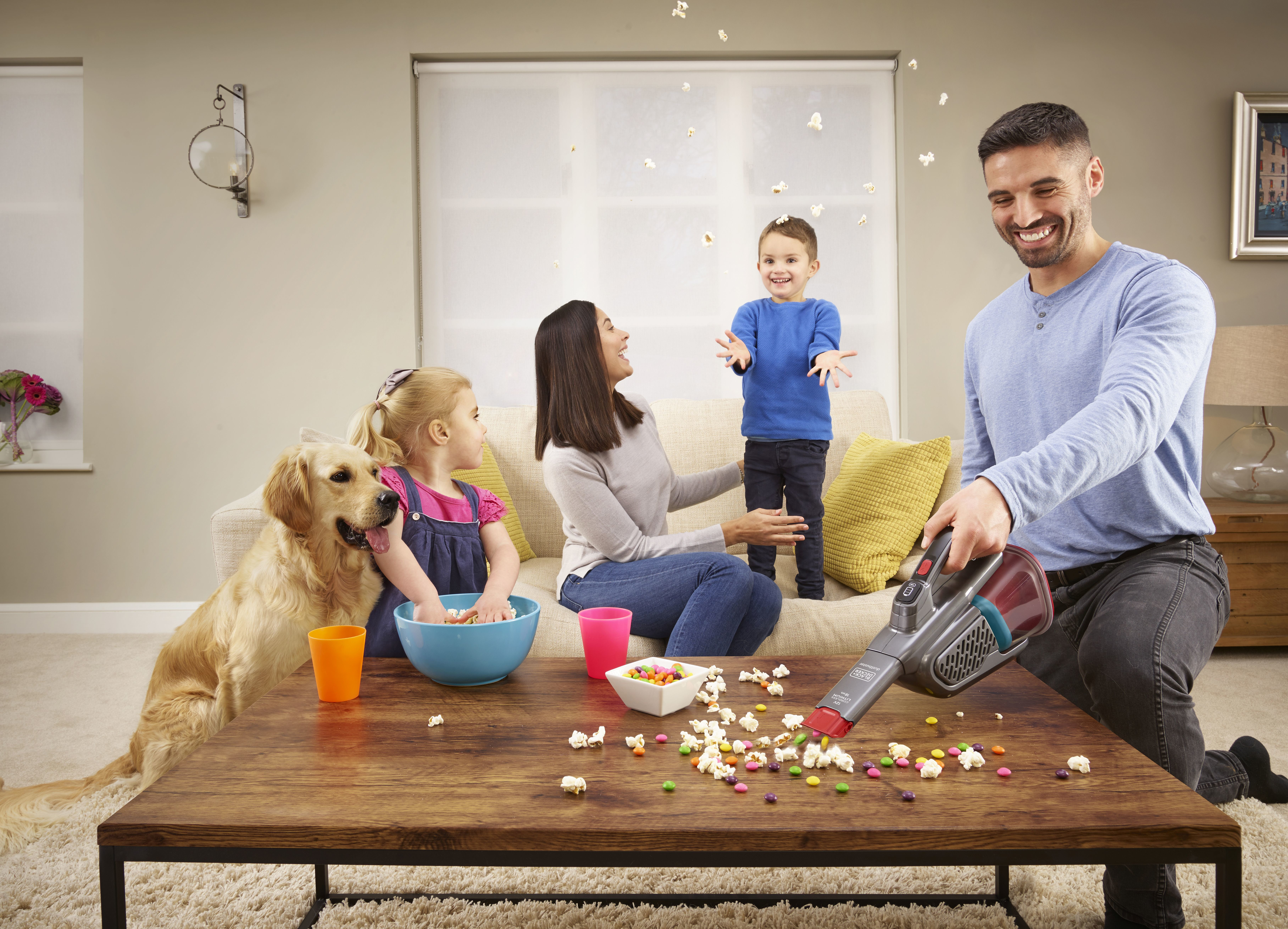 Familie im Wohnzimmer mit Popcorn und Staubsauger.