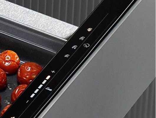Ganze geröstete Tomaten in einer Pfanne mit digitaler Steuerung und Zeitanzeige.