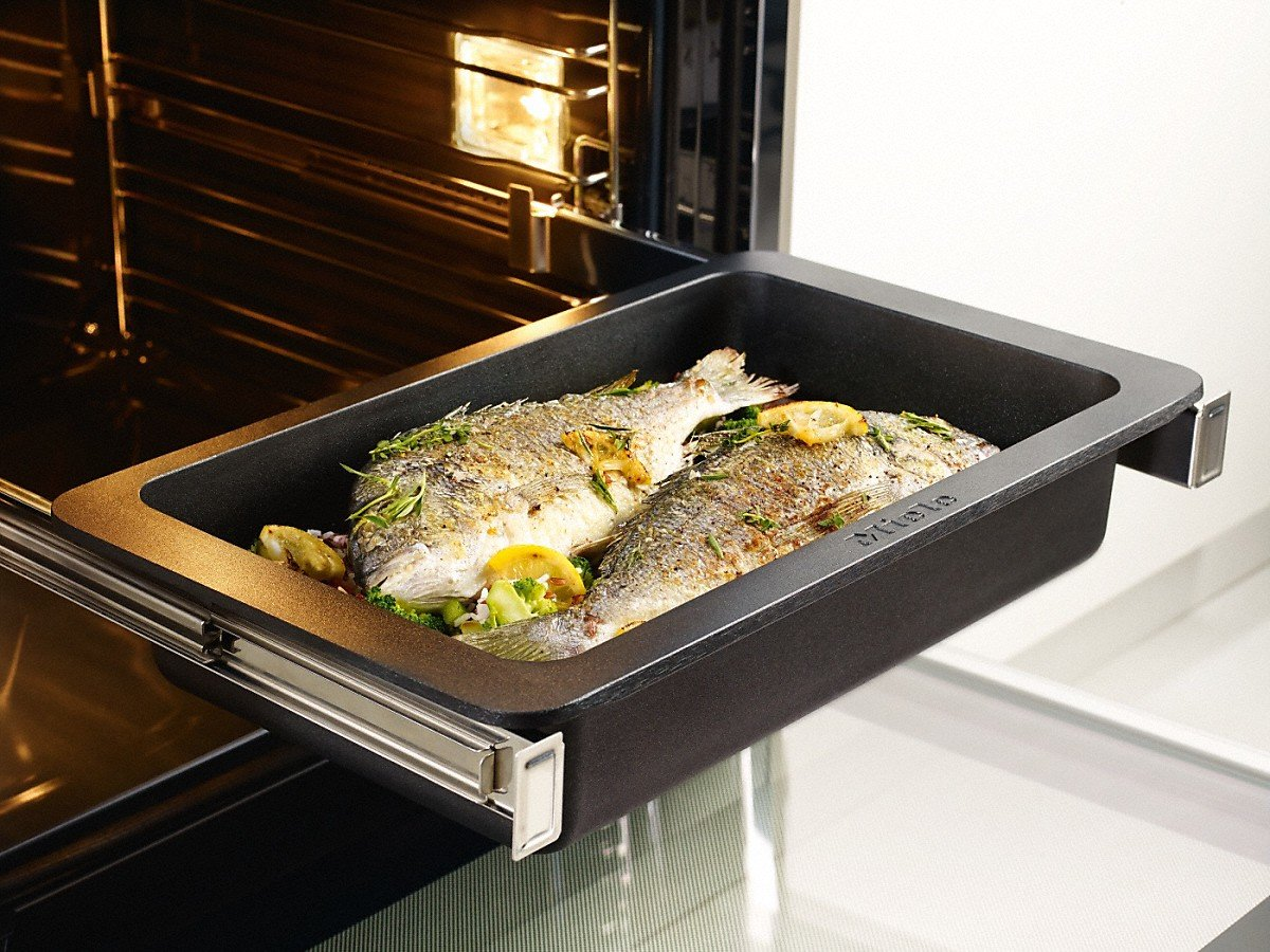 Backblech mit gekochtem Fisch und Zitronenscheiben im Ofen.