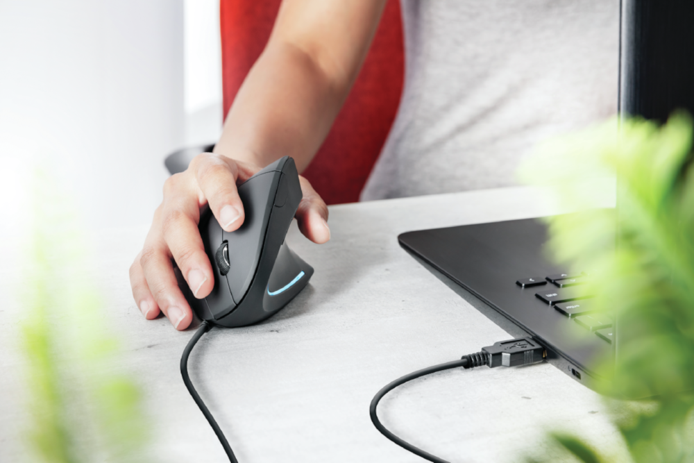 La main d'une personne sur une souris ergonomique noire connectée.