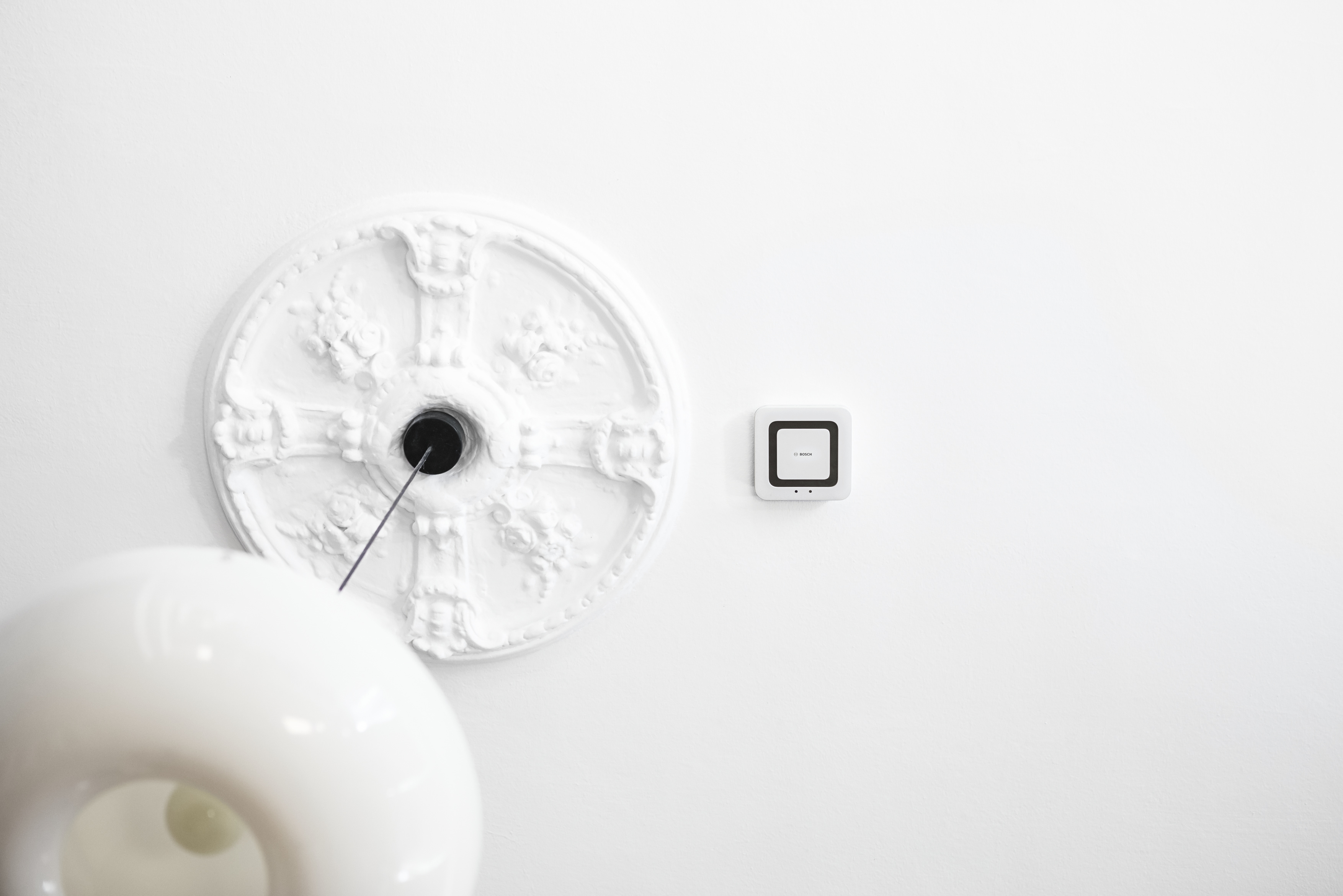 Weiße Decke mit einem dekorativen Kreis und einem Smart-Home-Gerät. Weißer Hintergrund.