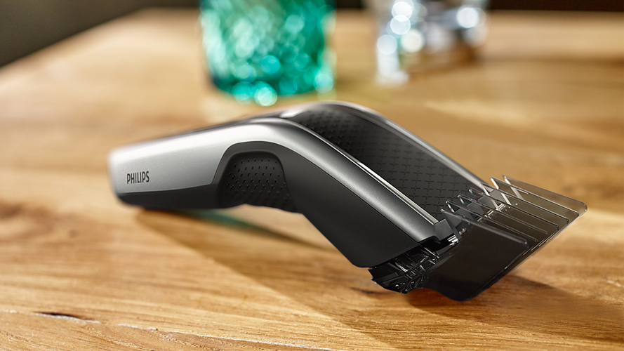 Une tondeuse Philips sur une surface en bois avec un verre turquoise en arrière-plan.