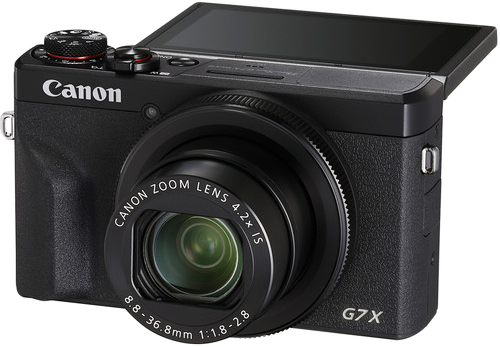 Fekete Canon kamera, kinyújtott objektívvel, nyitott képernyővel. Canon Zoom objektív látható.