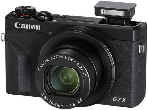 Egy fekete Canon G7X fényképezőgép objektívvel, felugró vakuval és vezérlőtárcsákkal a tetején.
