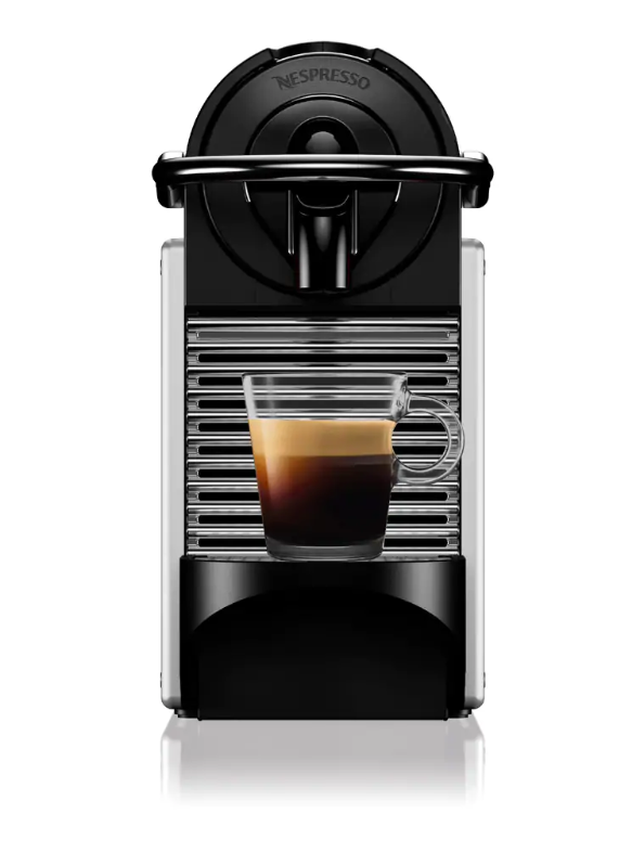 Schwarze und silberne Nespresso-Maschine mit einem Glas Kaffee auf weißem Grund.