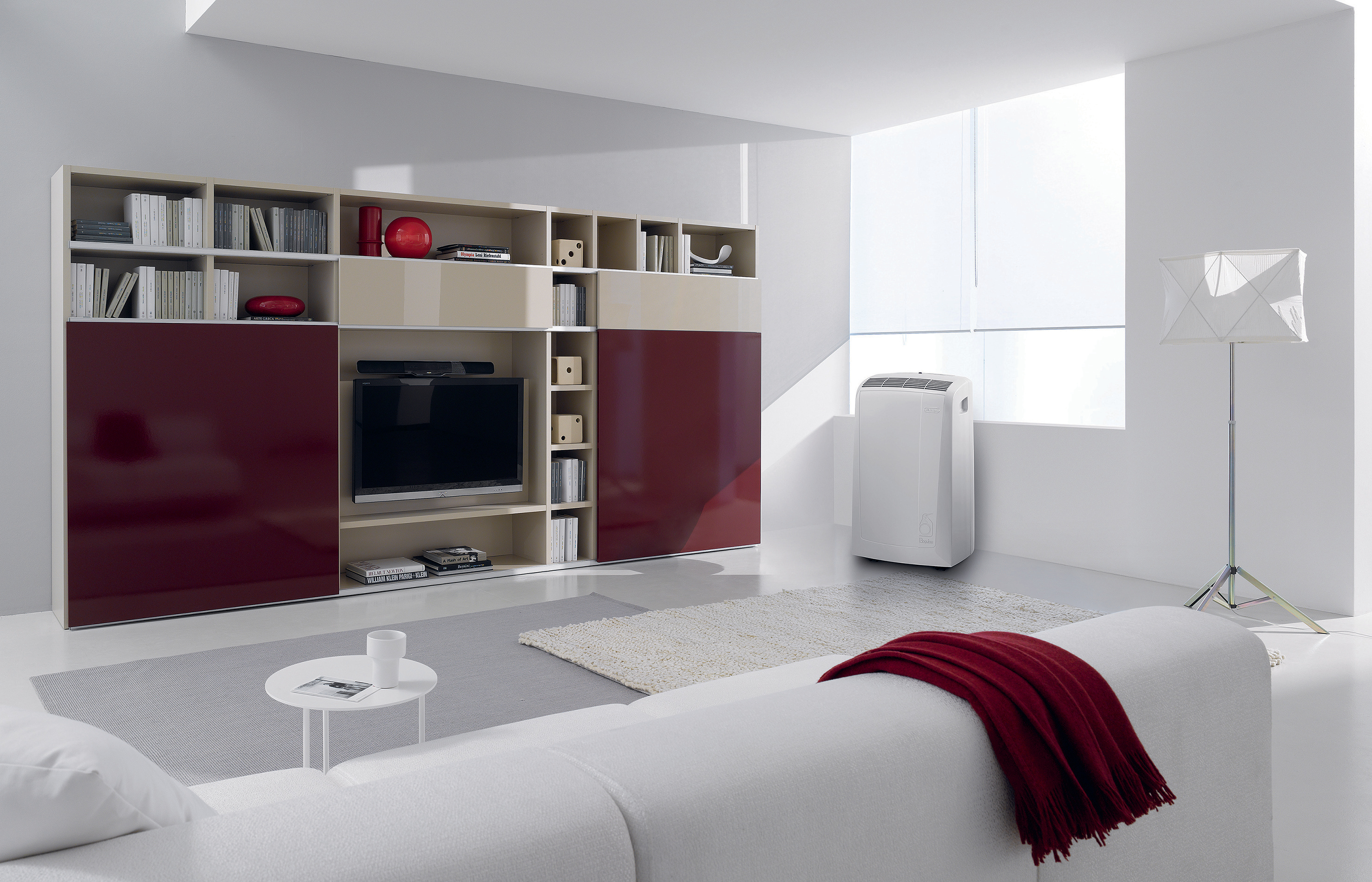 Wohnzimmer mit weißem Sofa, Entertainment-Center und weißem Klimagerät.