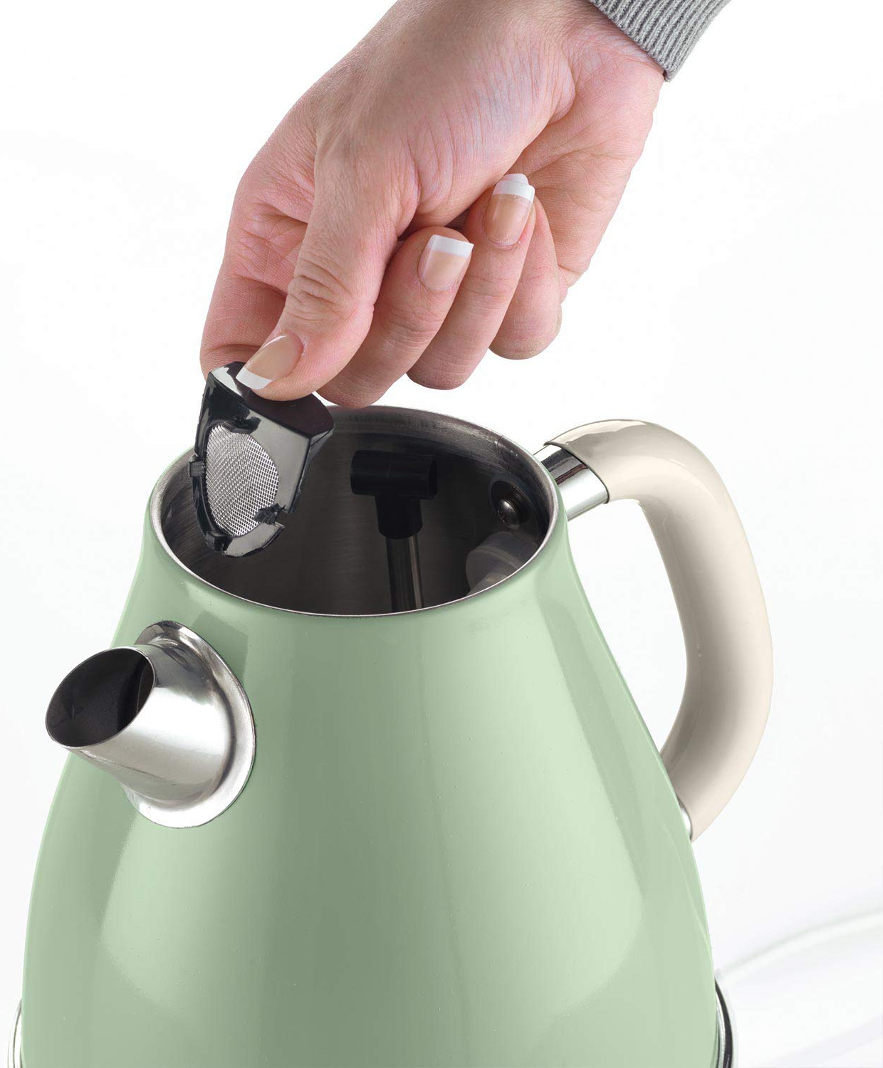 Eine Hand legt einen Tee-Infuser in die Öffnung eines grün-cremefarbenen Wasserkochers.