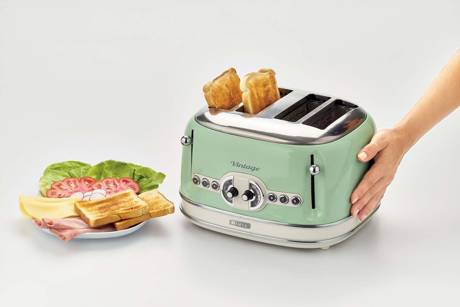 Grille-pain vert menthe avec toasts. Jambon, fromage, tomates et laitue sur une assiette.