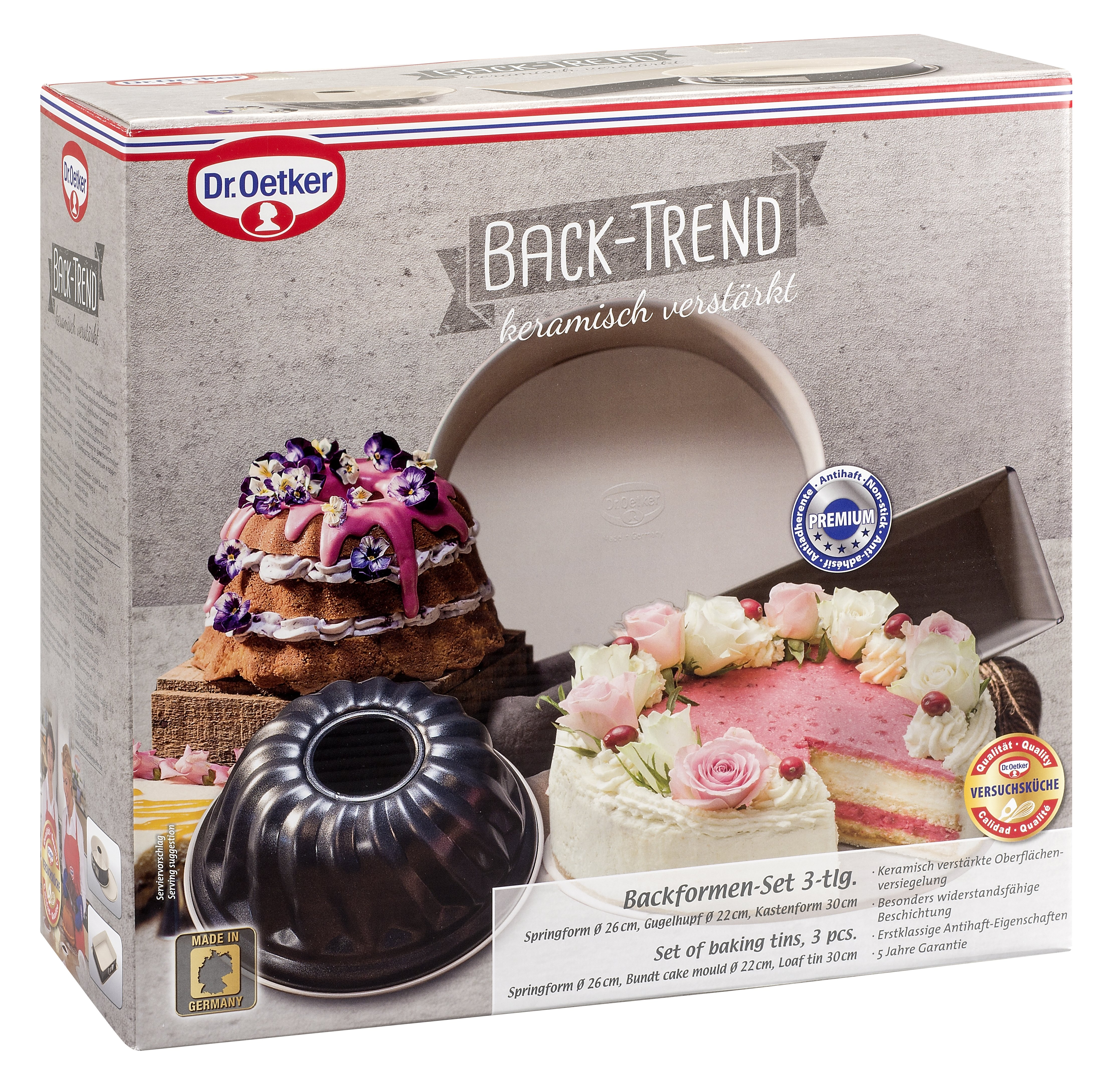 Eine Backformen-Set-Box mit Kuchen darauf. Auf der Vorderseite befindet sich ein Kuchen mit rosa Zuckerguss und Blumen.