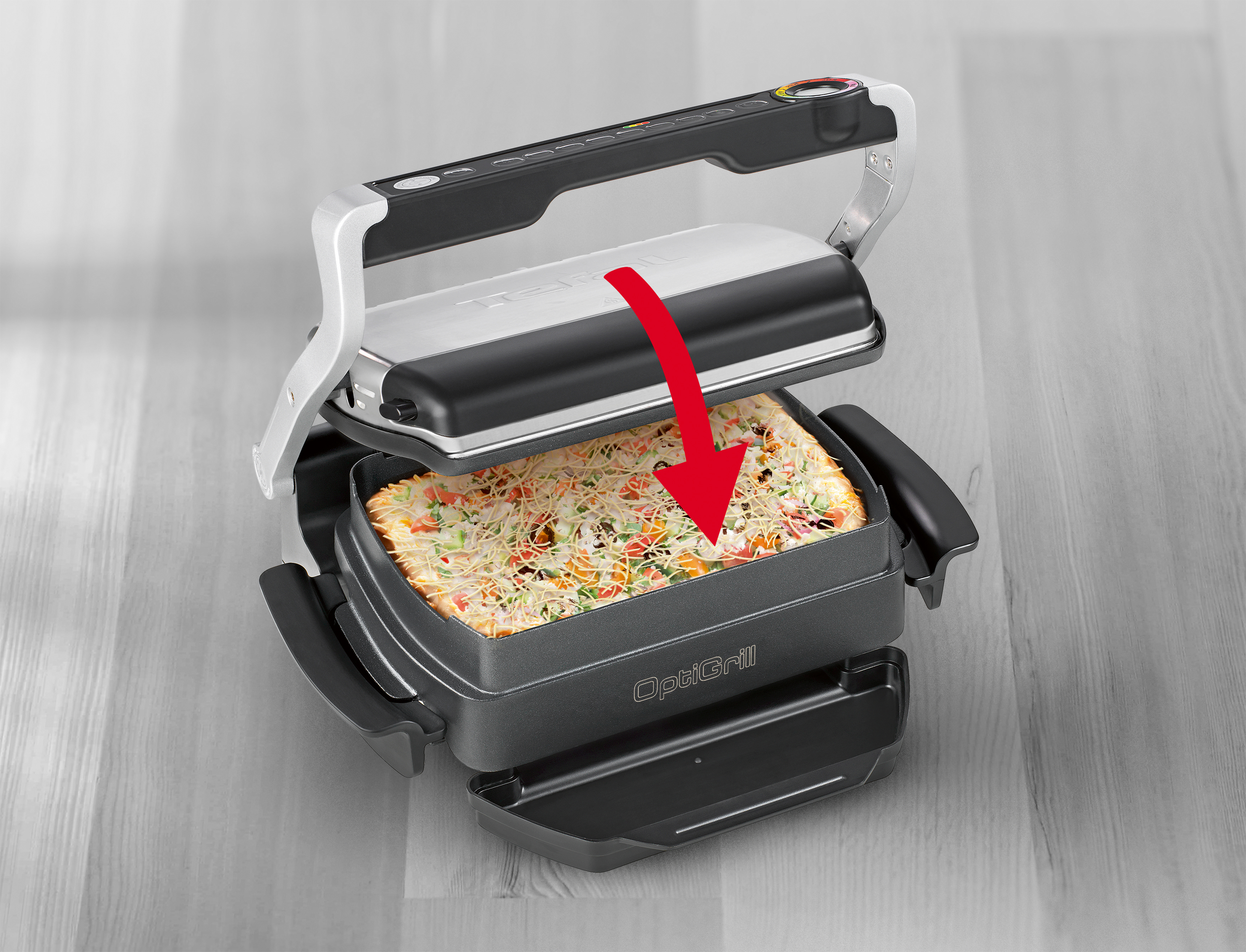 Eine Pizza auf einem Grill. Der Grill ist geöffnet, und ein roter Pfeil zeigt auf die Pizza.
