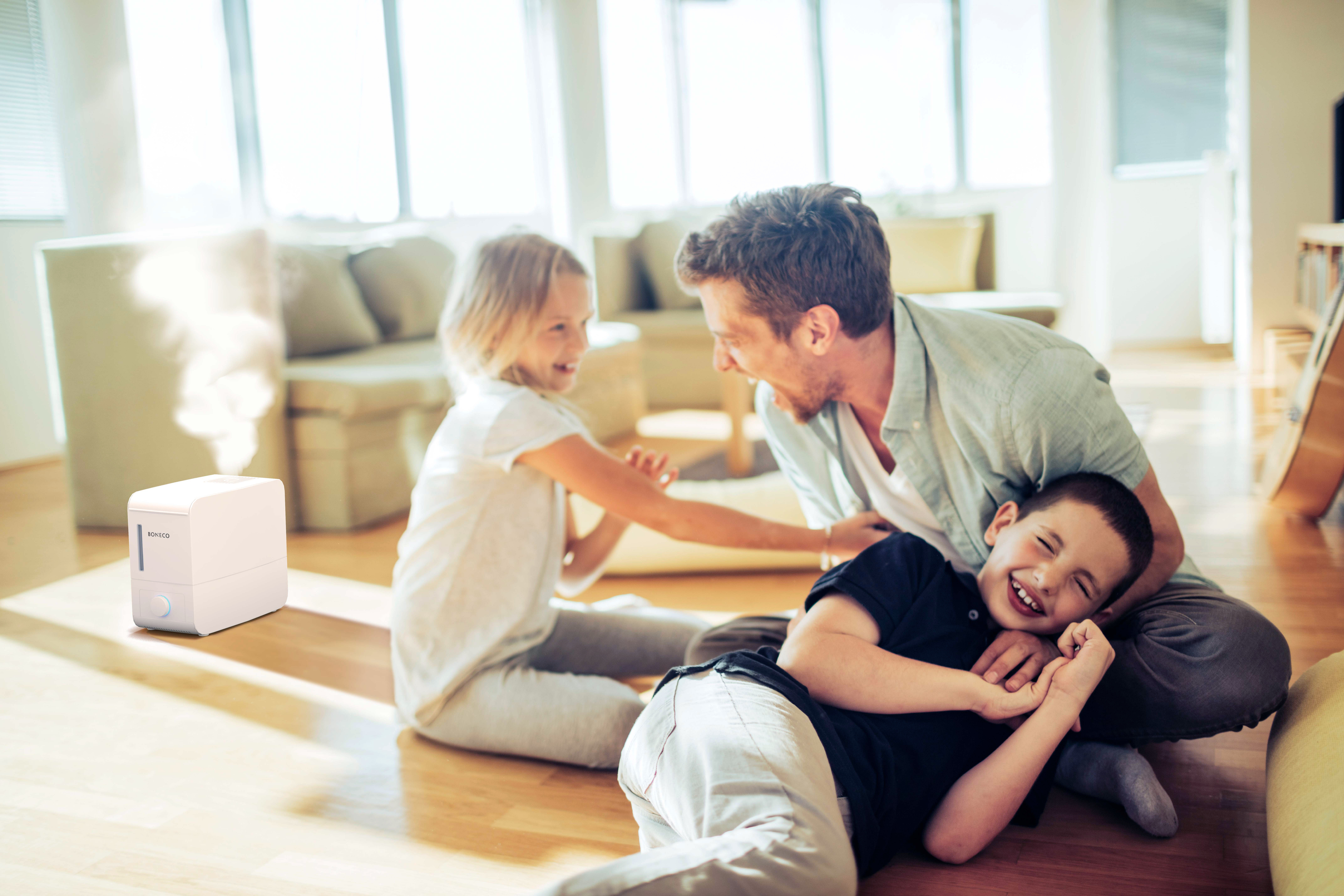 Vater und zwei Kinder lachen. Ein Luftbefeuchter ist im Vordergrund.