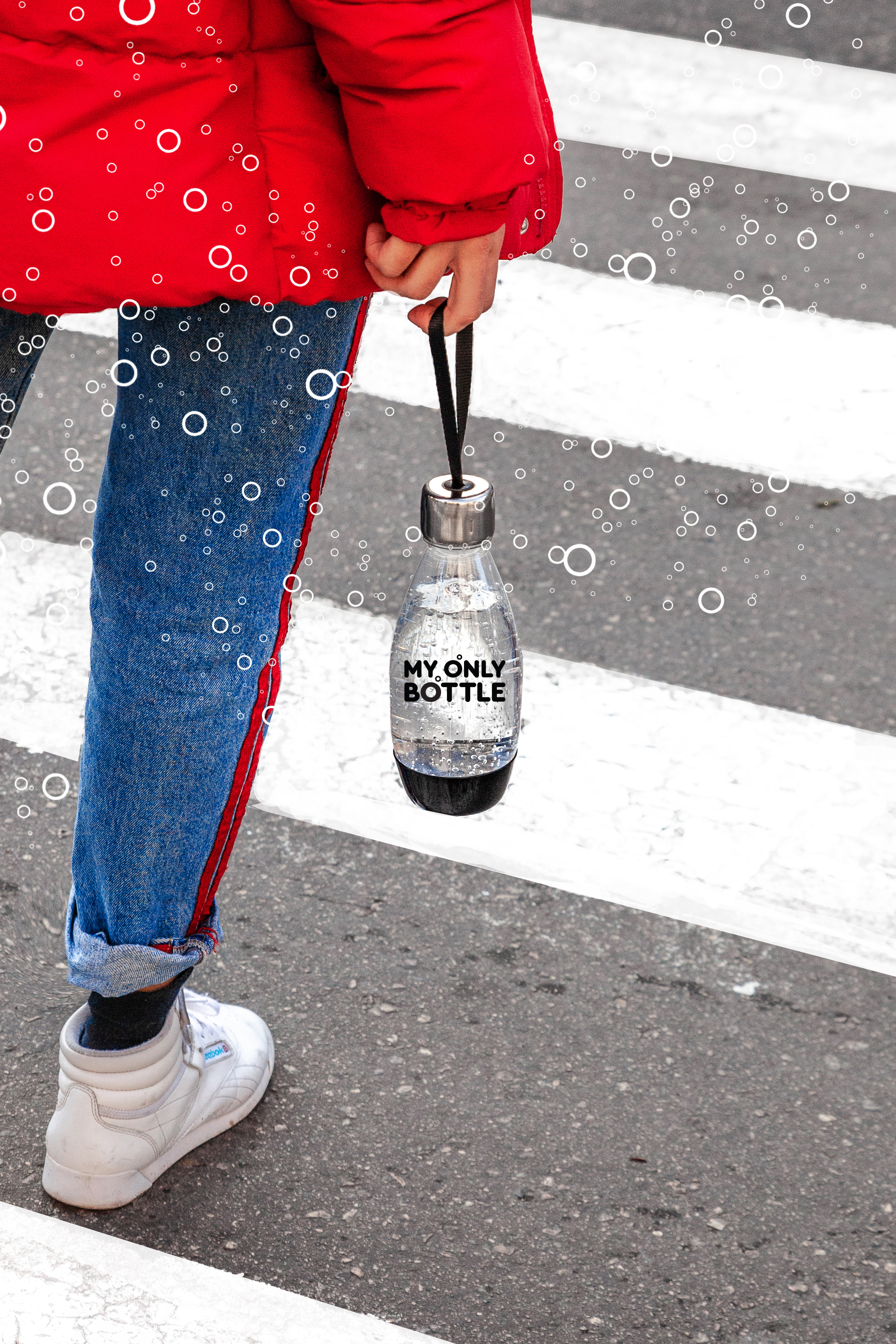 Personne en veste rouge, jean bleu et chaussures blanches marche sur passage piéton, tenant bouteille.