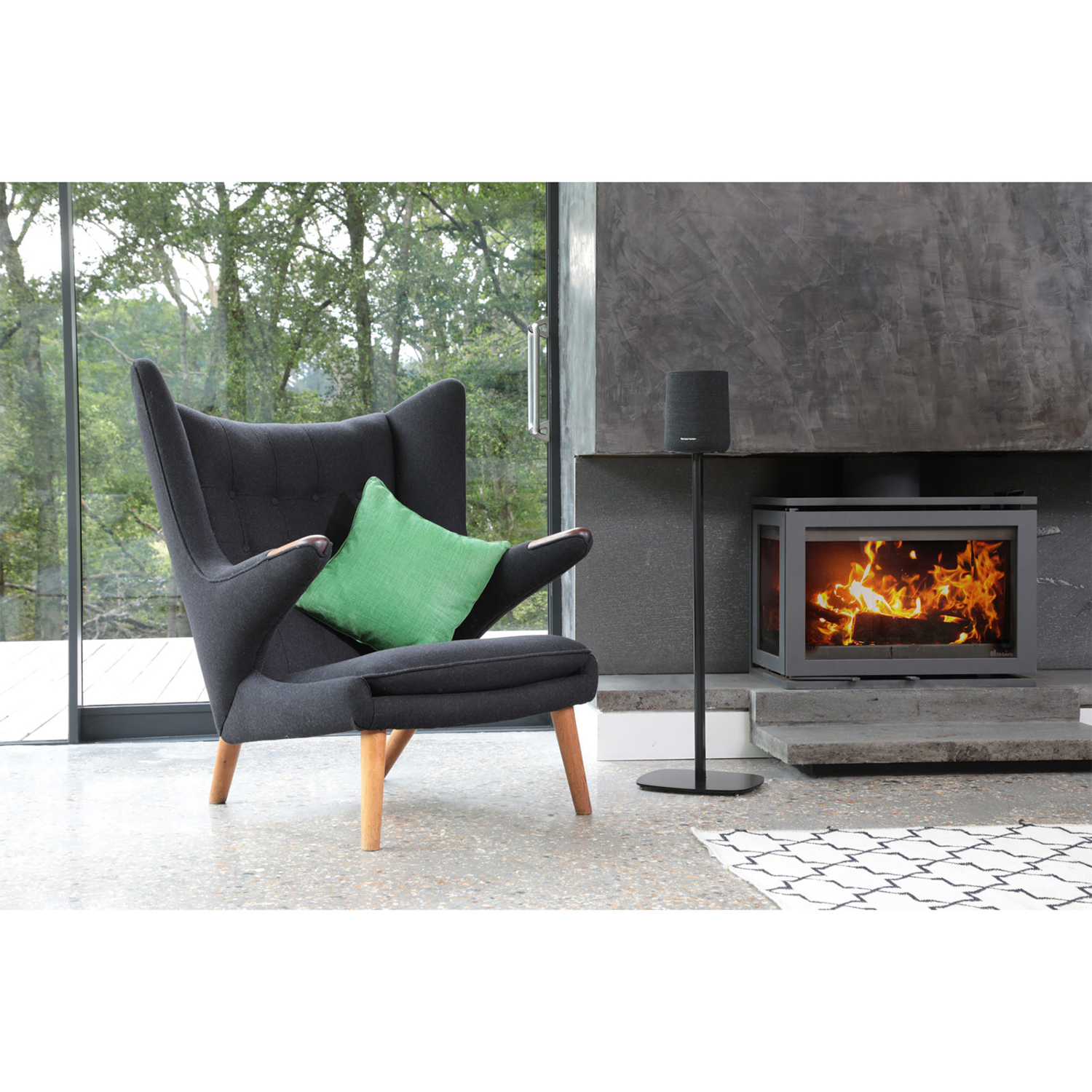 Living room scene with a black armchair, green cushion, and fireplace.