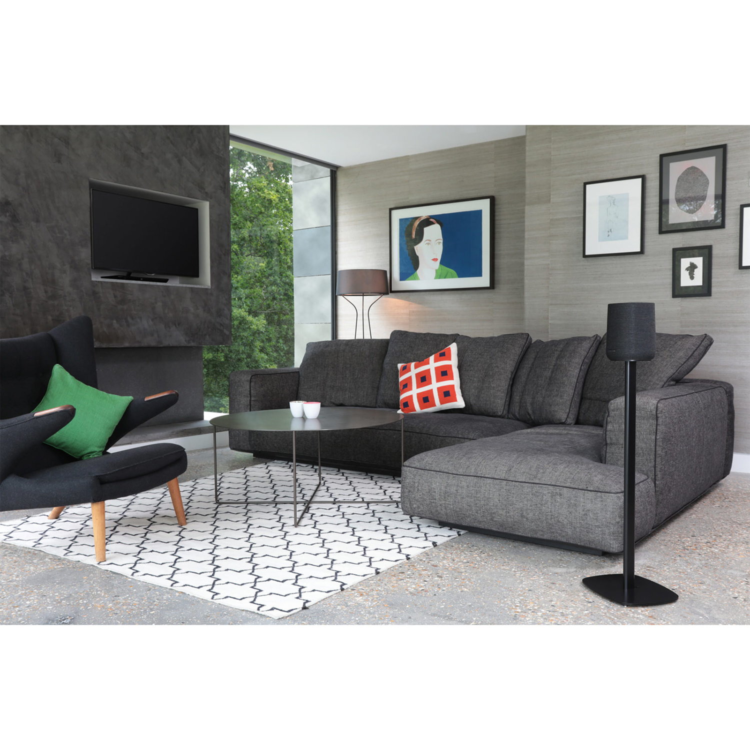 Living room with a grey sectional sofa, art, and a black speaker on a stand.