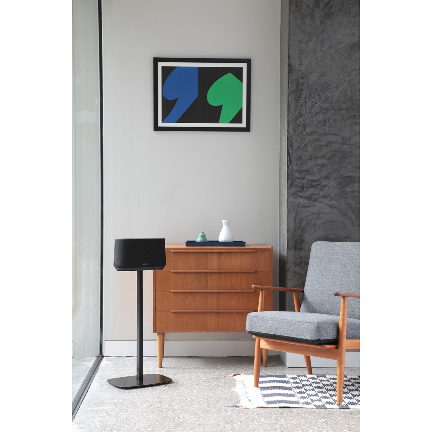 Interieur met een luidspreker, kast en kunst. Een zwarte luidspreker op een standaard staat op de voorgrond.