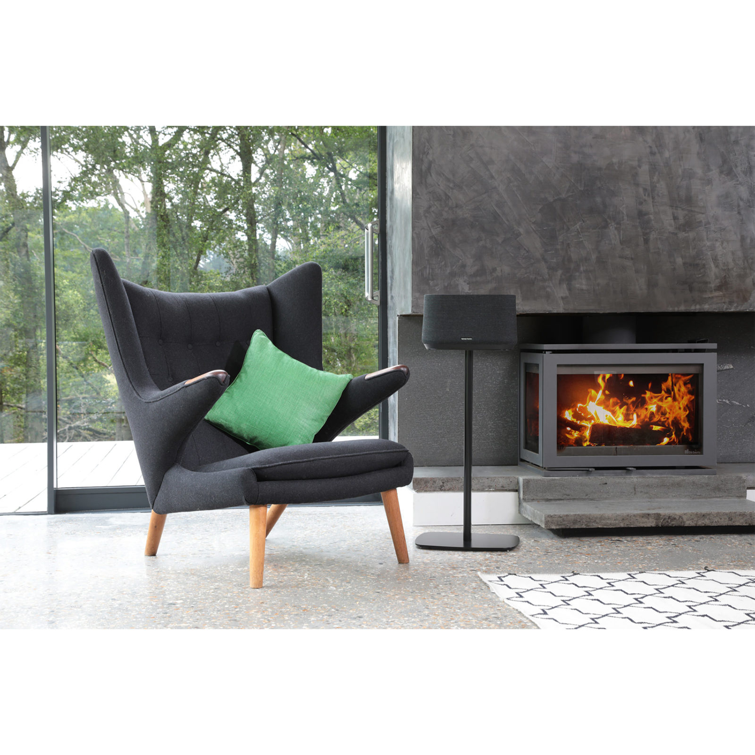 Moderne woonkamer met fauteuil en open haard. Luidspreker op standaard naast open haard.