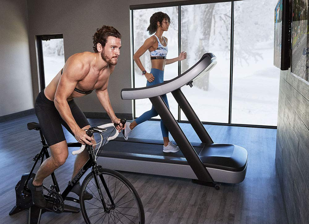 Homme sur vélo et femme sur tapis de course en salle de sport.