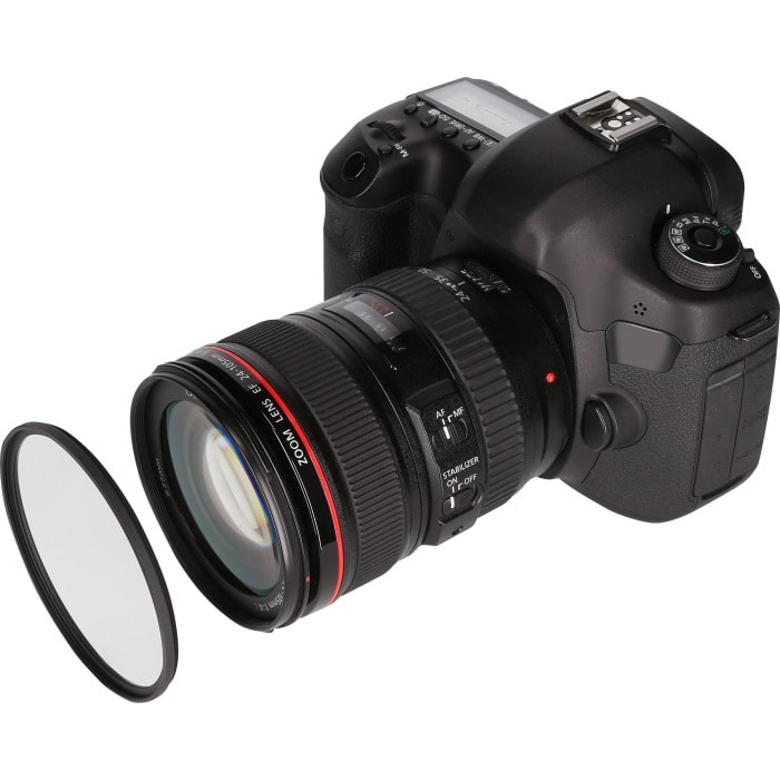 Zwarte camera met een lens bevestigd, en een losse lensfilter, alles op een witte achtergrond.