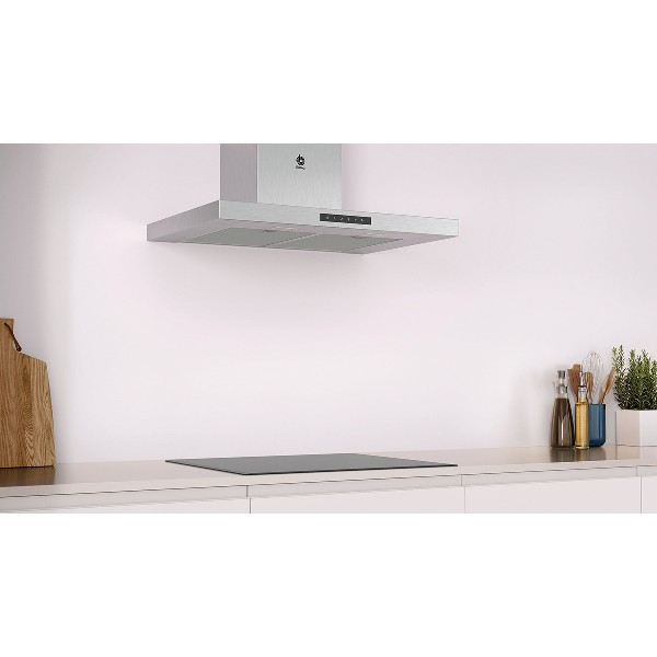 Cocina con campana extractora plateada sobre una encimera negra. Fondo blanco.