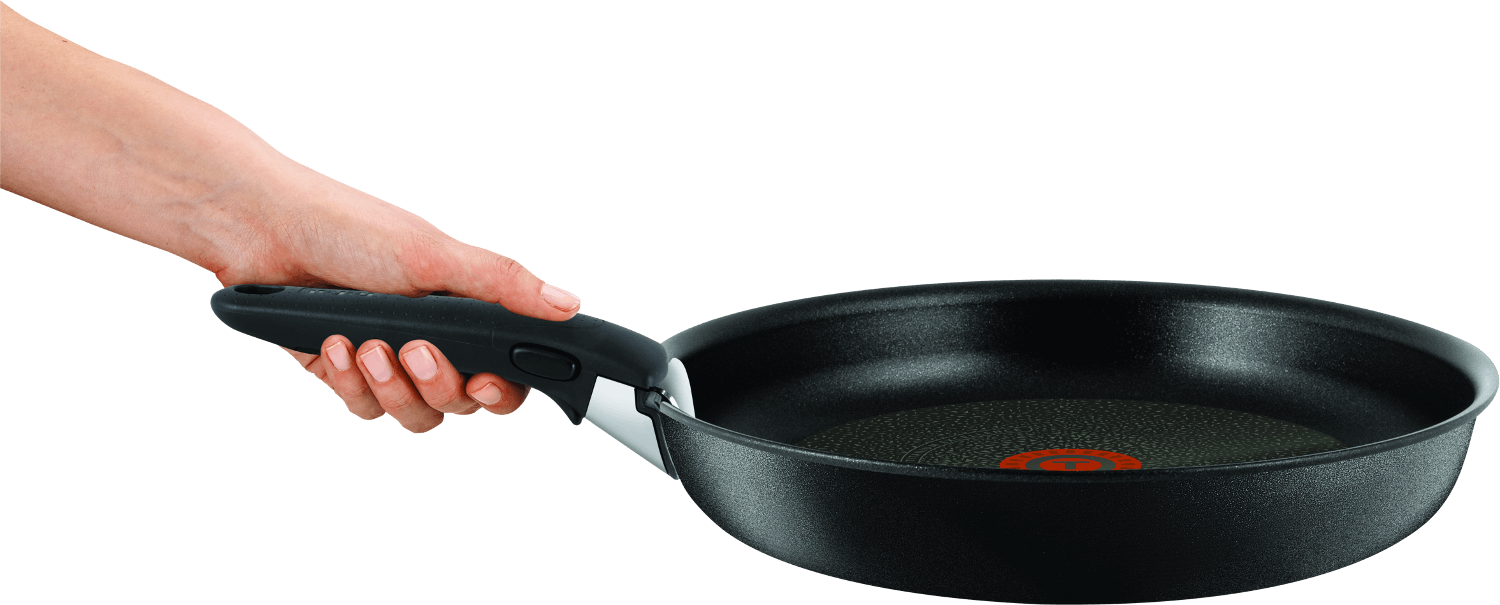 Een hand houdt een zwarte koekenpan vast. De pan heeft een zwarte handgreep en een rood-oranje cirkel in het midden.
