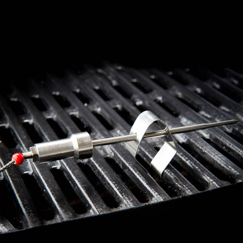 Grill thermometer probe on a black grate.
