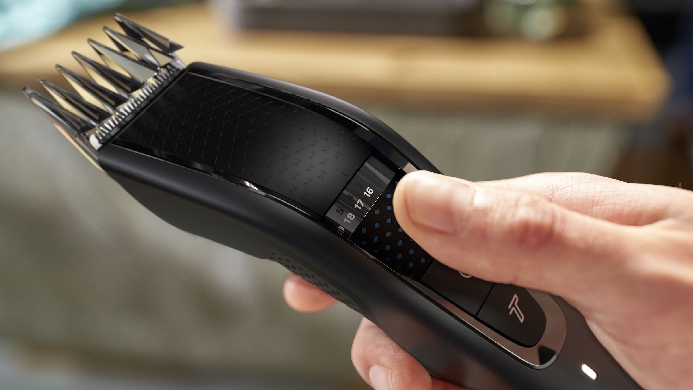 Eine Hand, die einen schwarzen Haarschneider mit digitaler Anzeige hält, die die Einstellungen zeigt.