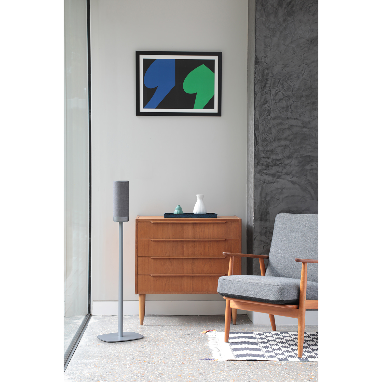 Interieur met een luidspreker, houten kast, fauteuil en een ingelijst abstract kunstwerk.