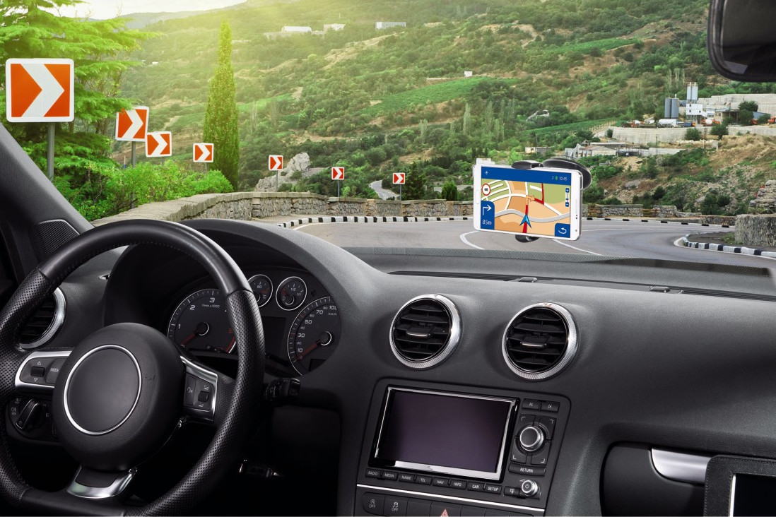 Intérieur de voiture avec un GPS sur le tableau de bord, montrant une route avec des courbes et des flèches.