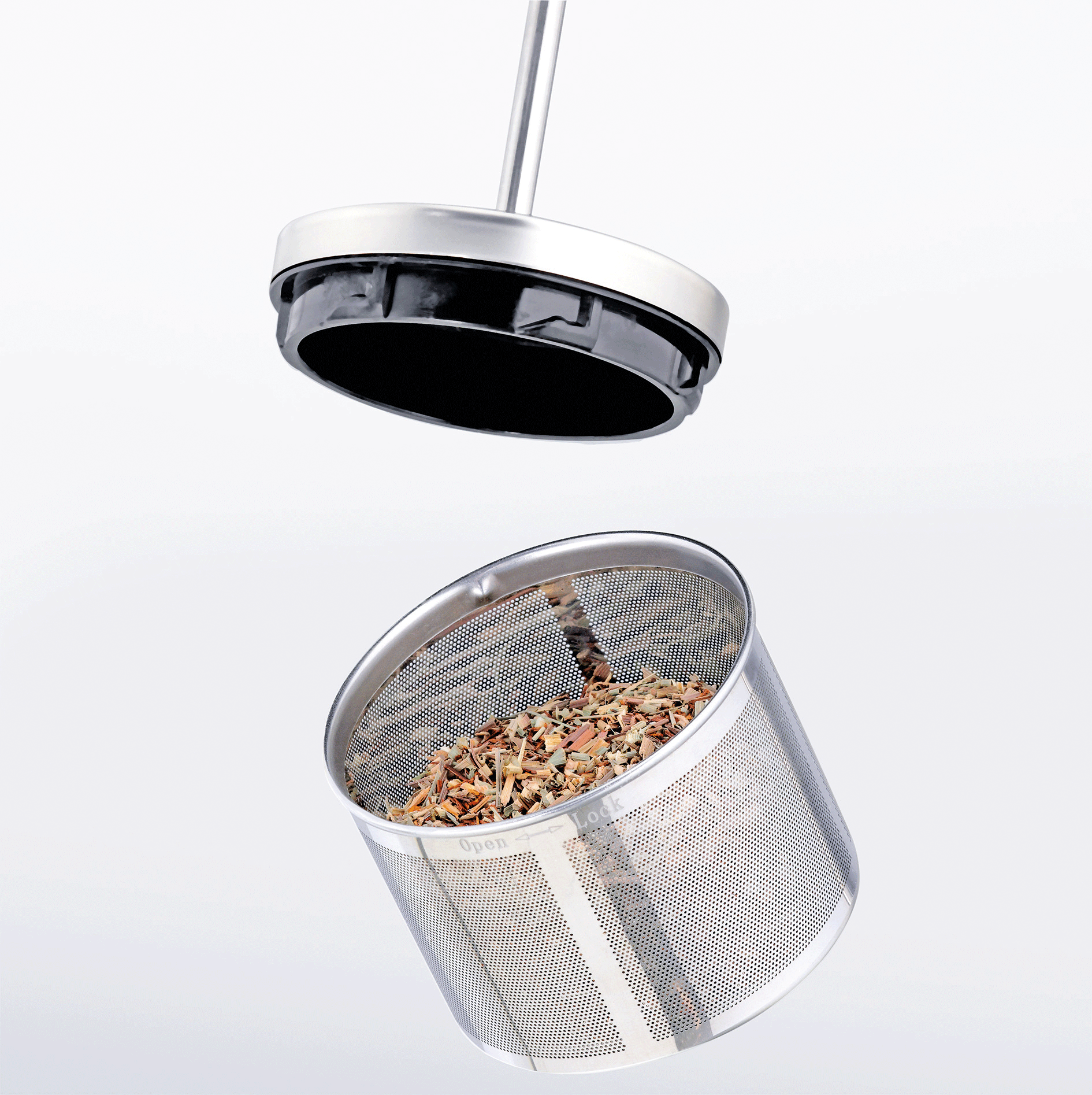 Ein Edelstahl-Tee-Aufgussgerät mit Teeblättern und einem schwarzen Deckel darüber.