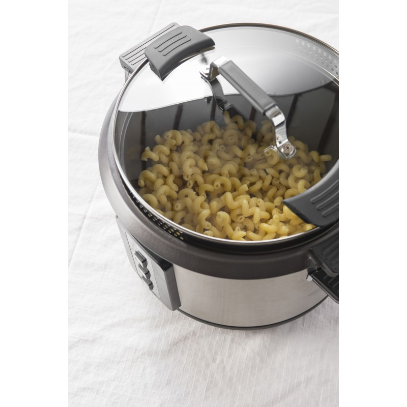 A stainless steel pot with a glass lid, filled with elbow macaroni, sitting on white fabric.