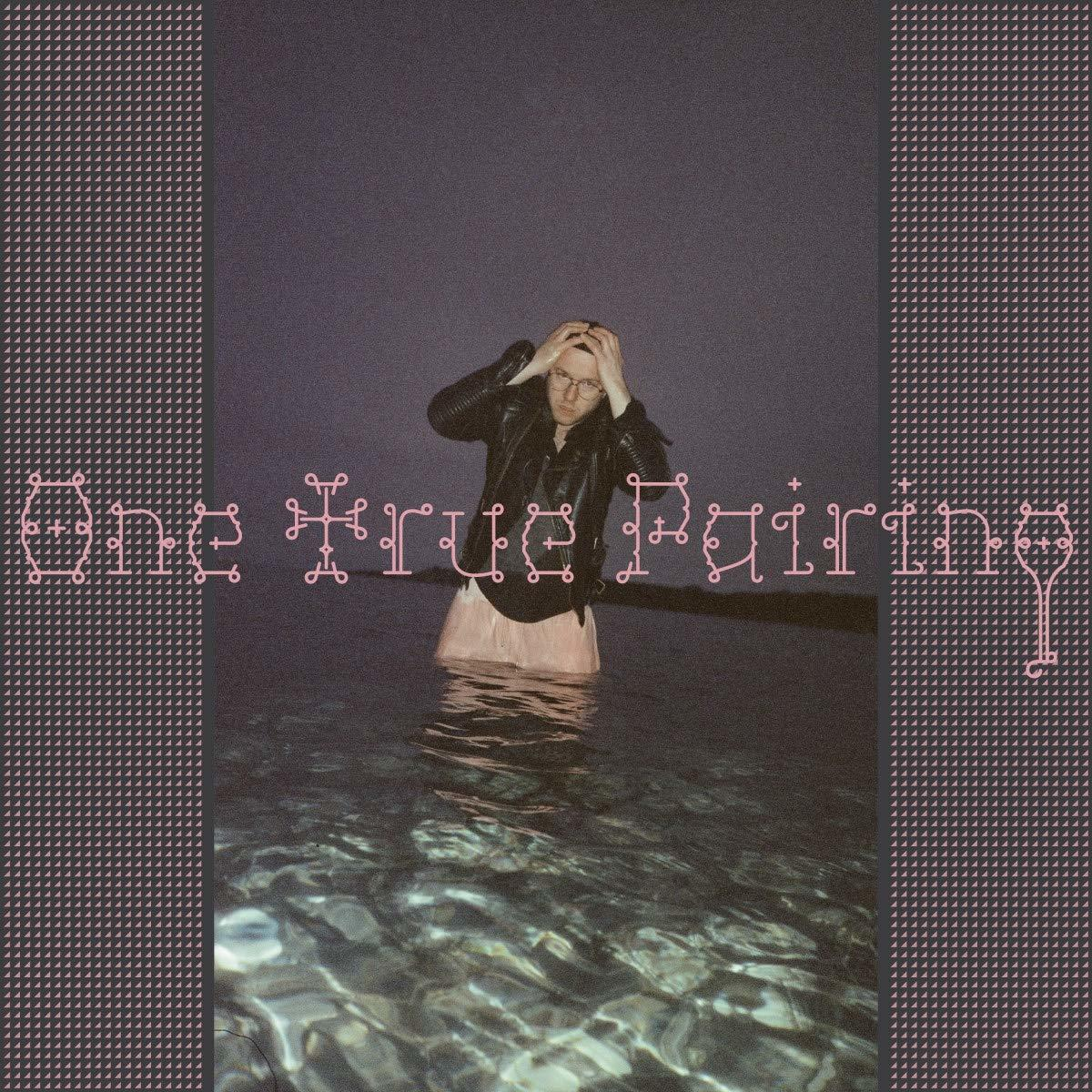 Mann im Wasser, Hände am Kopf, Lederjacke. Text 'One True Pairing' in Pink.