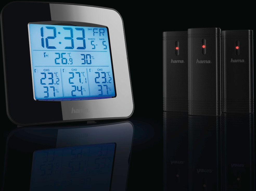 Digital clock shows time and weather data. Three black sensors stand behind it.