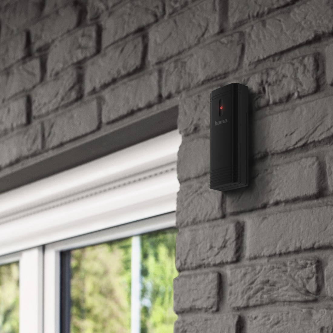 A black security device with a red light, mounted on a brick wall.