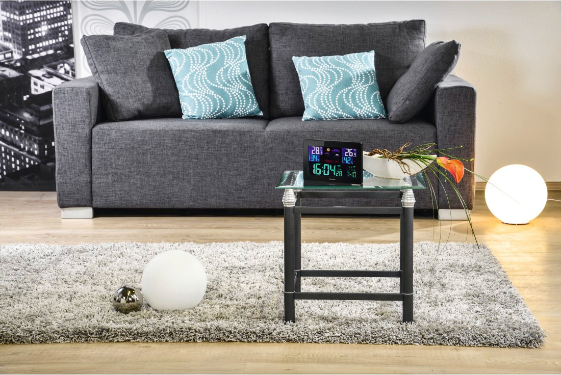 A living room setting with a gray sofa, pillows, a glass table, and a rug.