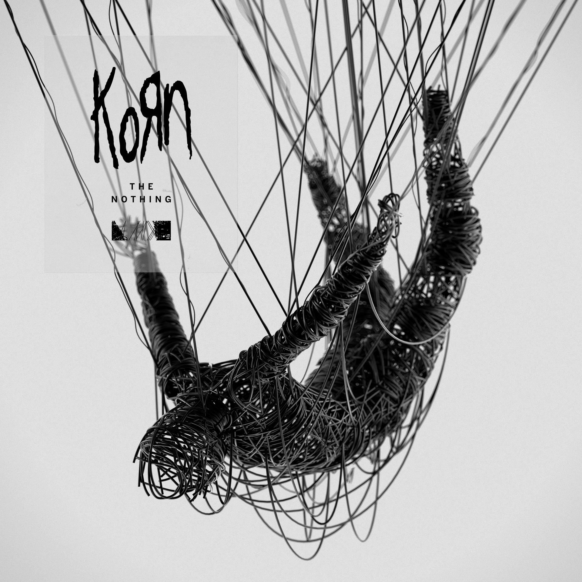 Albumhoes voor Korn, 'The Nothing'. Een zwart figuur van draden hangt in de lucht. Witte achtergrond.