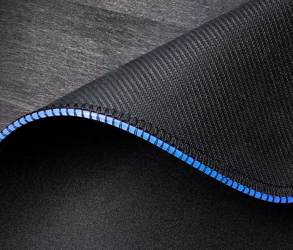 Gros plan sur un tapis de souris noir et bleu. Aspect fibre de carbone. Coutures bleues.