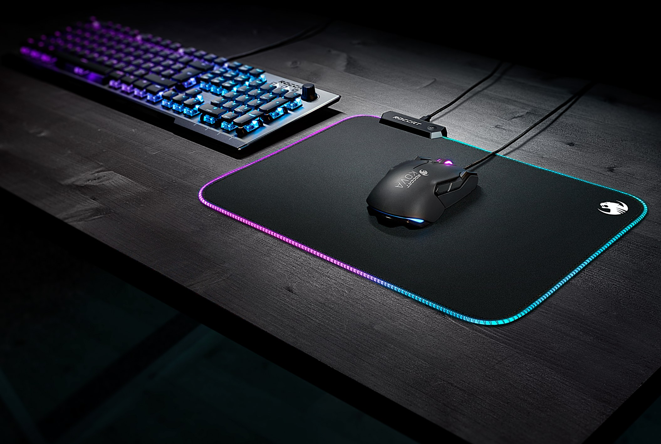 Configuration de jeu avec clavier, souris et tapis de souris avec éclairage RVB sur un bureau noir.