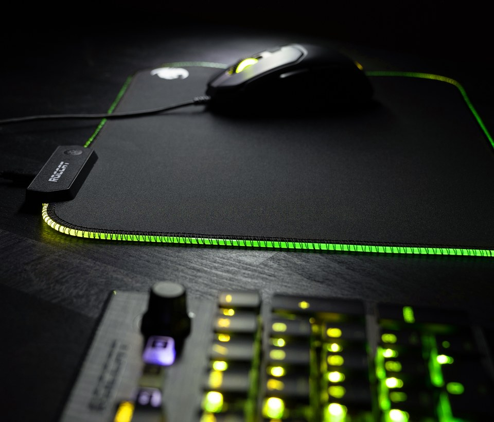 Souris de jeu sur un tapis de souris noir avec lumière verte sur les bords et clavier.