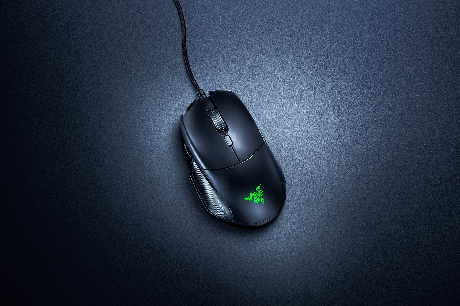 Ratón de ordenador negro sobre una superficie negra, con logo Razer verde.