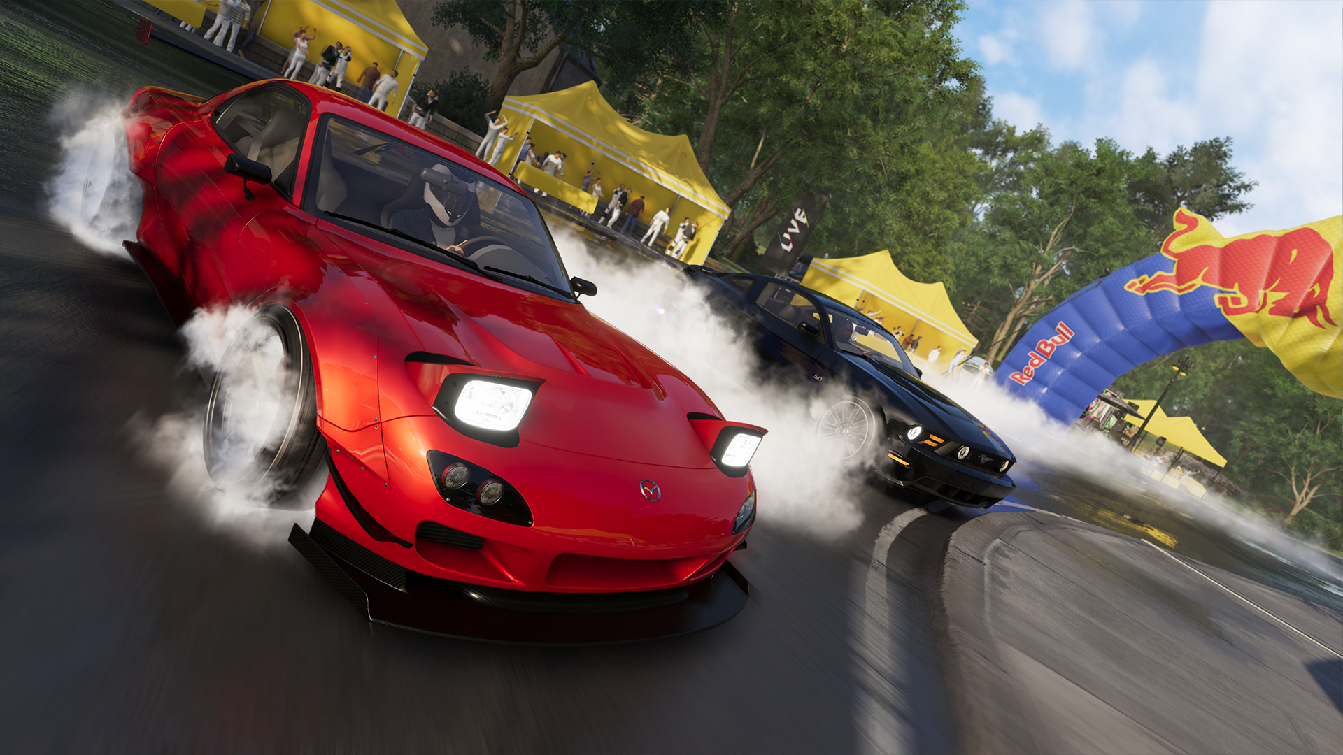 Mazda RX-7 rouge dérapant sur une piste avec une autre voiture, arche Red Bull et foule.