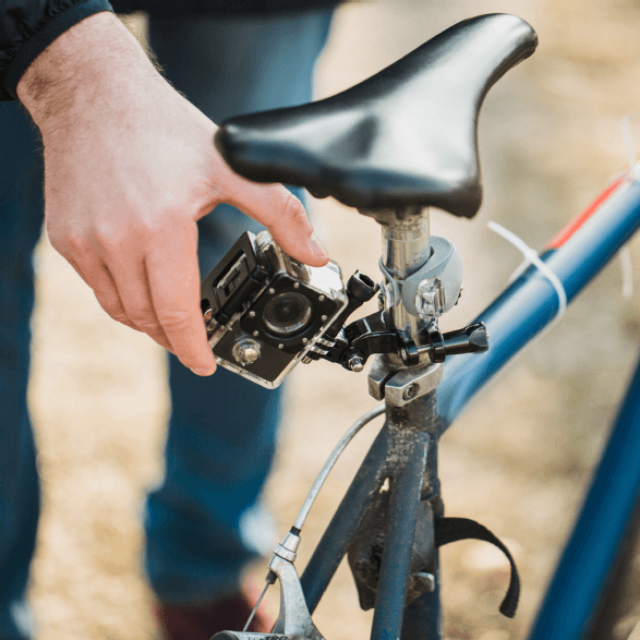 Une personne fixe une caméra sur la tige de selle d'un vélo. Le vélo est bleu.