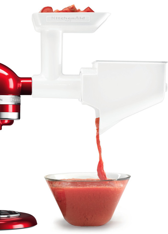 KitchenAid-Fleischwolf, weiß, mit roter KitchenAid-Küchenmaschine. Tomatensauce fließt in eine Schüssel.