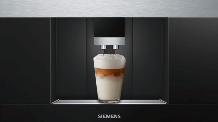 Máquina de espresso dispensando café en un vaso, espuma encima.