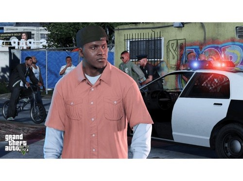 Una escena de Grand Theft Auto V con gente. Hay un coche de policía presente. Un hombre con una camisa melocotón mira hacia otro lado.