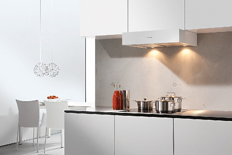 Una cocina moderna con gabinetes blancos, campana extractora y ollas en la estufa.