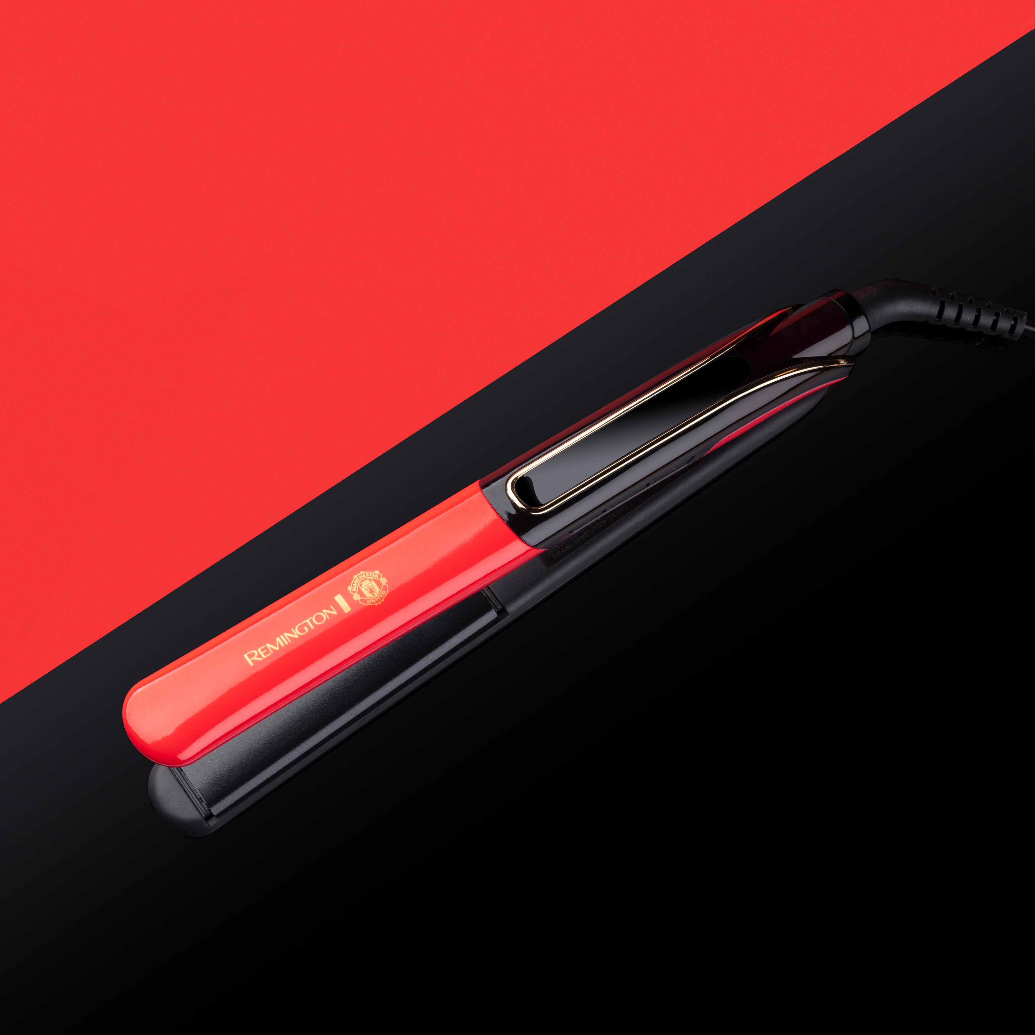 Roter und schwarzer Haarglätter auf reflektierender Oberfläche. Abgewinkelter Hintergrund mit roten und schwarzen Abschnitten.