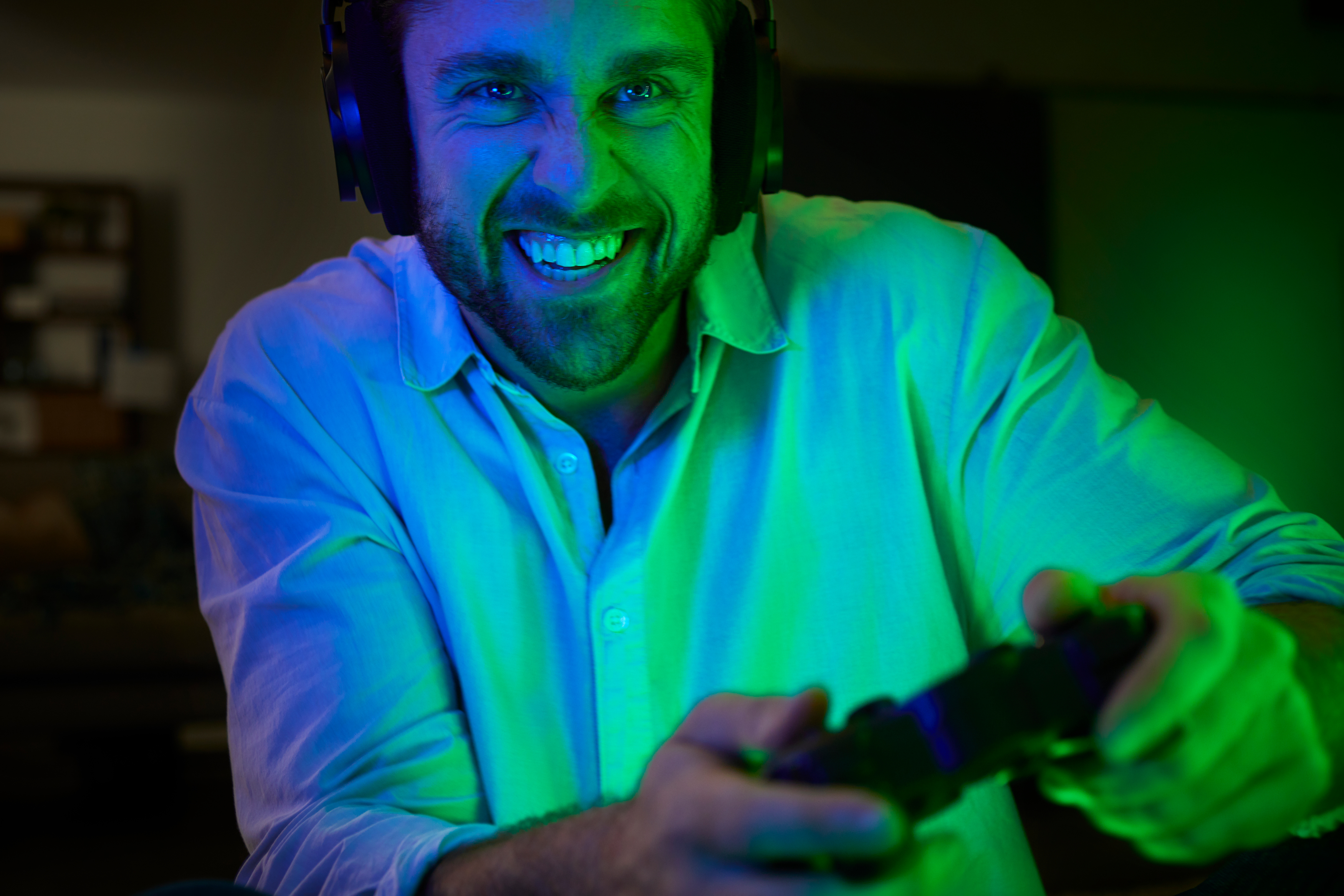 Ein Mann mit Kopfhörern und einem Lächeln, der mit einem Controller ein Videospiel spielt.