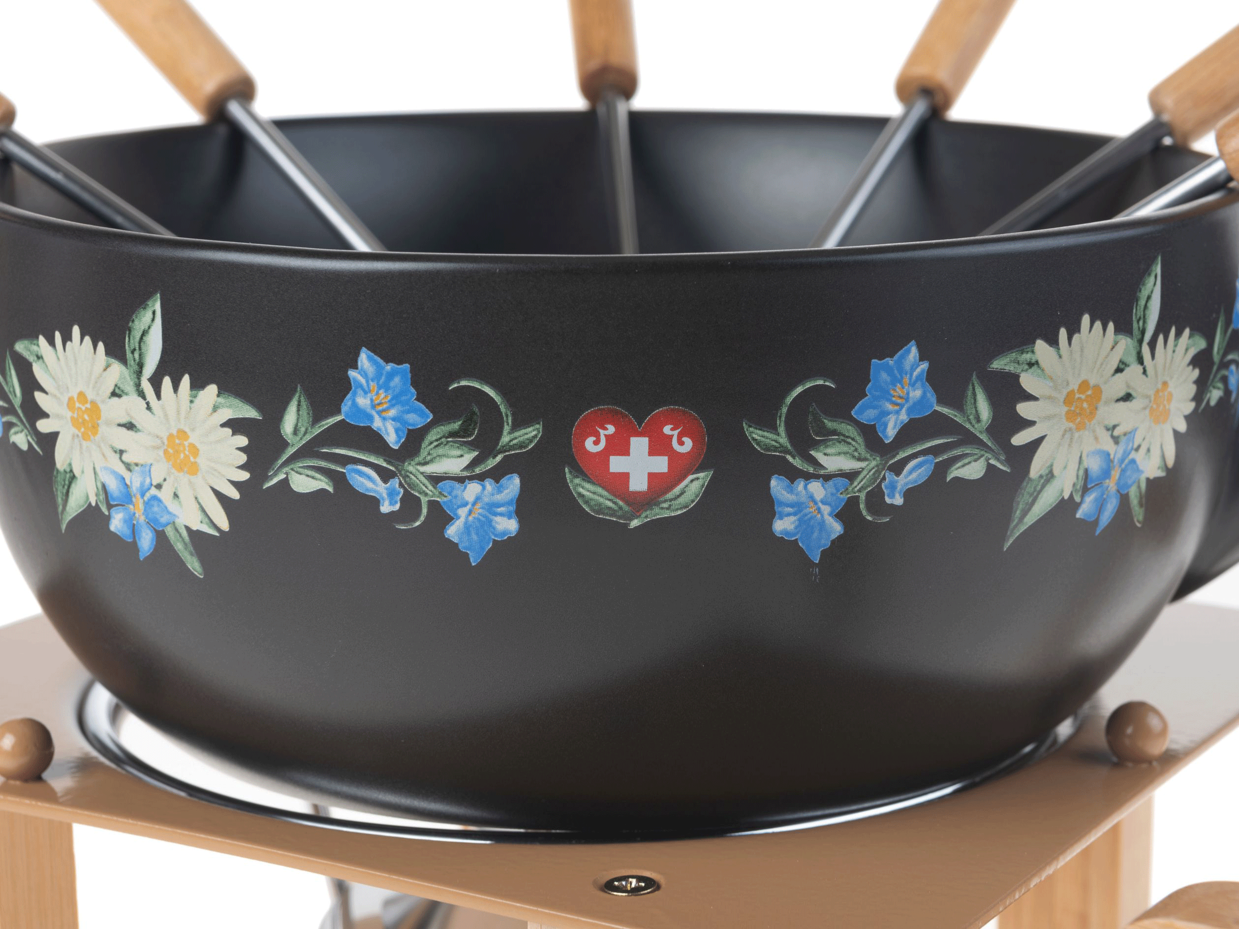 Schwarzer Fonduetopf mit Blumendesign auf einem Holzständer. Es hat Holzgriffe für die Gabeln.