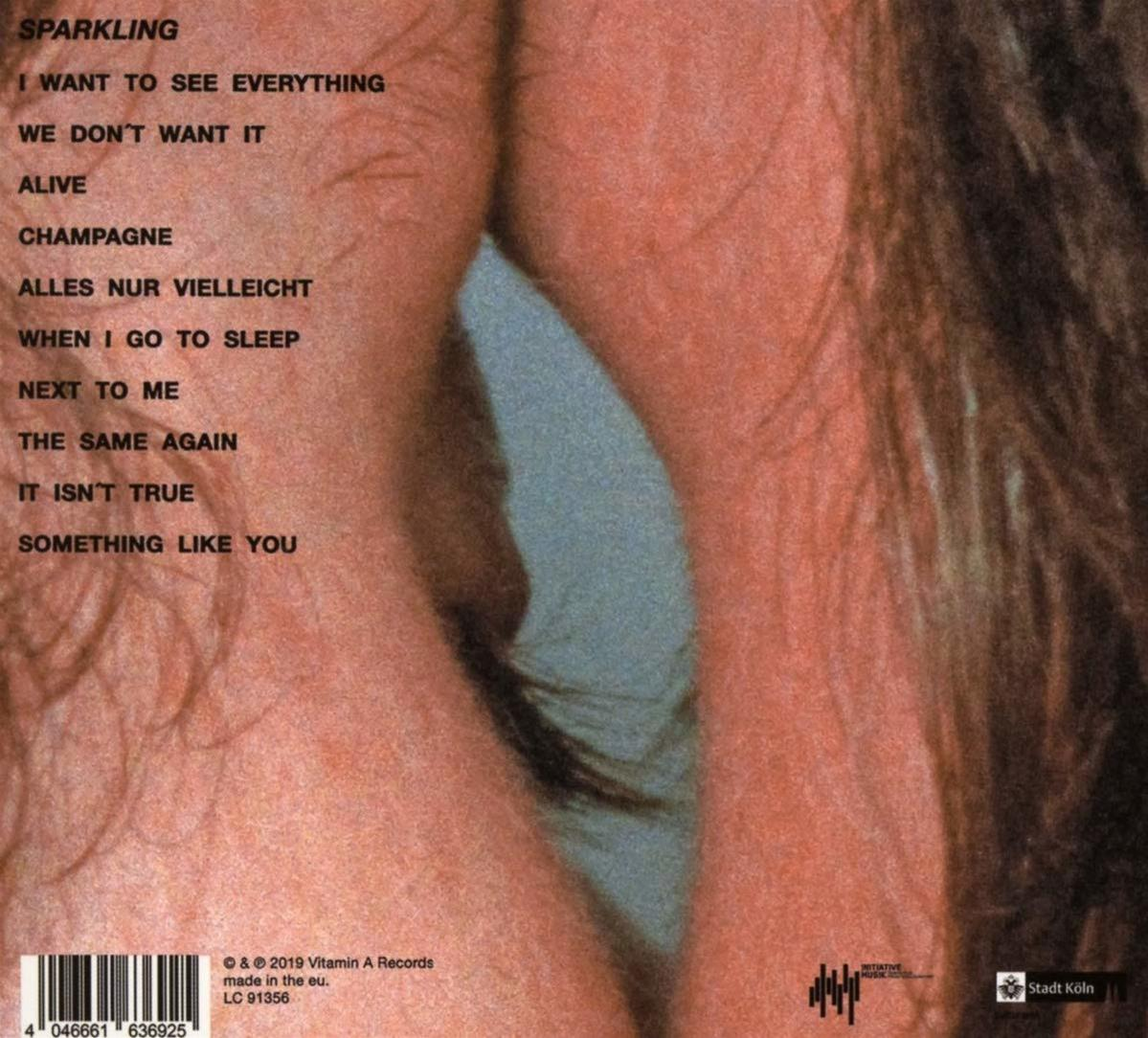 Albumcover mit Titeln der Songs. Lippen sind im Vordergrund. Der Hintergrund ist blau.